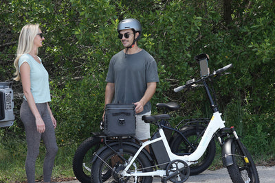 Man and woman chatting next to electric bike with phone holder in outdoor setting.