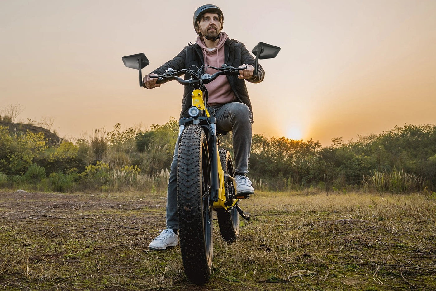 Man riding fat tire electric bike with extra-large mirrors at sunset