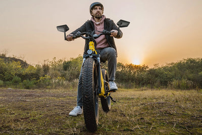Man riding fat tire electric bike with extra-large mirrors at sunset