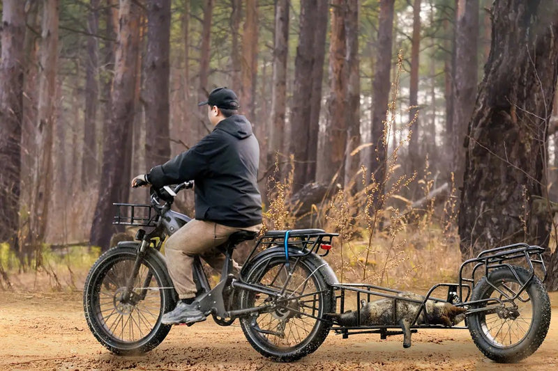 Magicycle Deer e-bike towing a trailer with logs in a forest environment