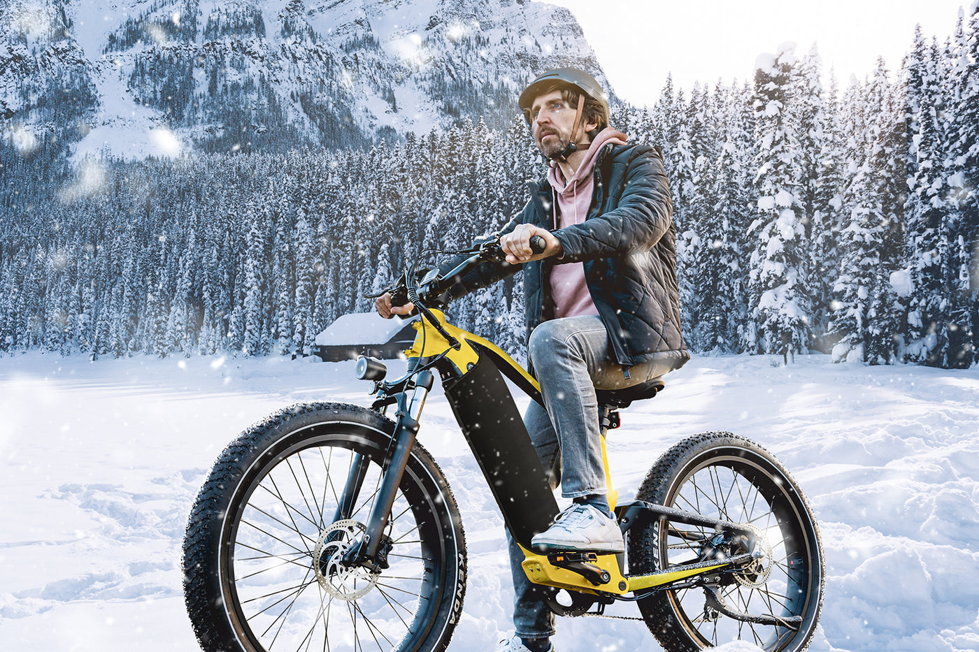 Man riding yellow electric bike in snowy mountains, perfect for winter adventures.
