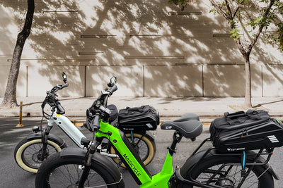 Three Magicycle electric bikes parked on a city street with waterproof pannier bags.