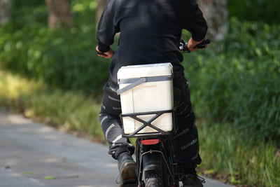 Insulated hard cooler mounted on e-bike rear rack for outdoor excursions.