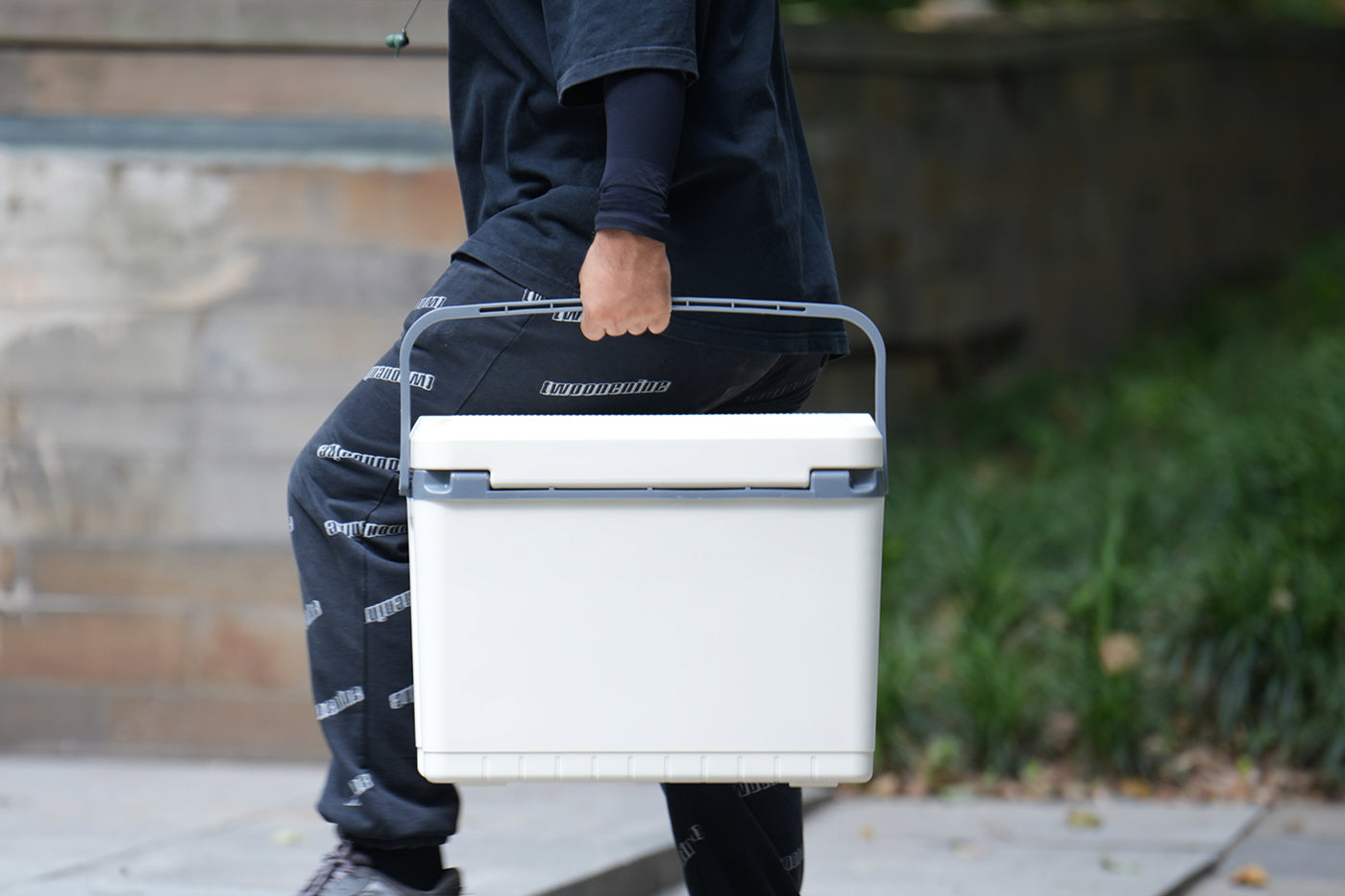 Person carrying hard cooler with durable handle for outdoor activities