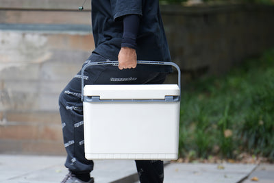 Person carrying hard cooler with durable handle for outdoor activities
