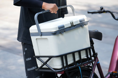 Insulated cooler carried on e-bike, designed for outdoor adventures and tailgating.
