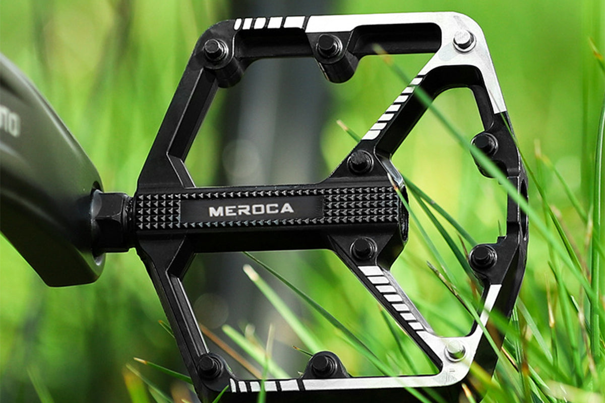 Close-up of MEROCA ergonomic black bike pedal on green grass.