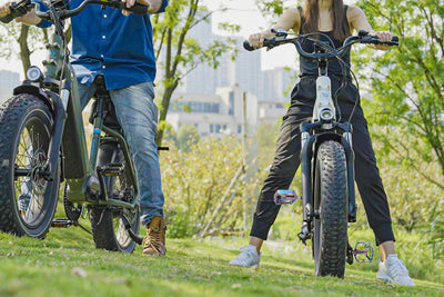 Two riders on electric bikes with rainbow pedals, showcasing outdoor adventure.