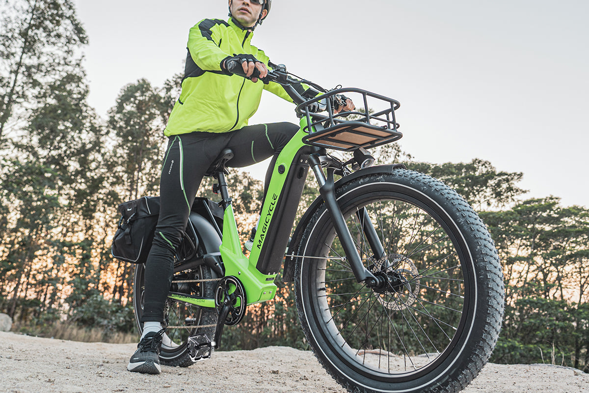 Cyclist in a green jacket riding a Magicycle electric bike on a dirt path.
