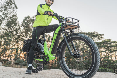 Cyclist in a green jacket riding a Magicycle electric bike on a dirt path.