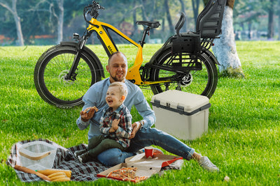 Family picnic with child and rear-mounted child bike seat near yellow electric bike.