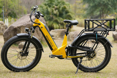 Magicycle electric bike with large black rear rack basket on grassy terrain.