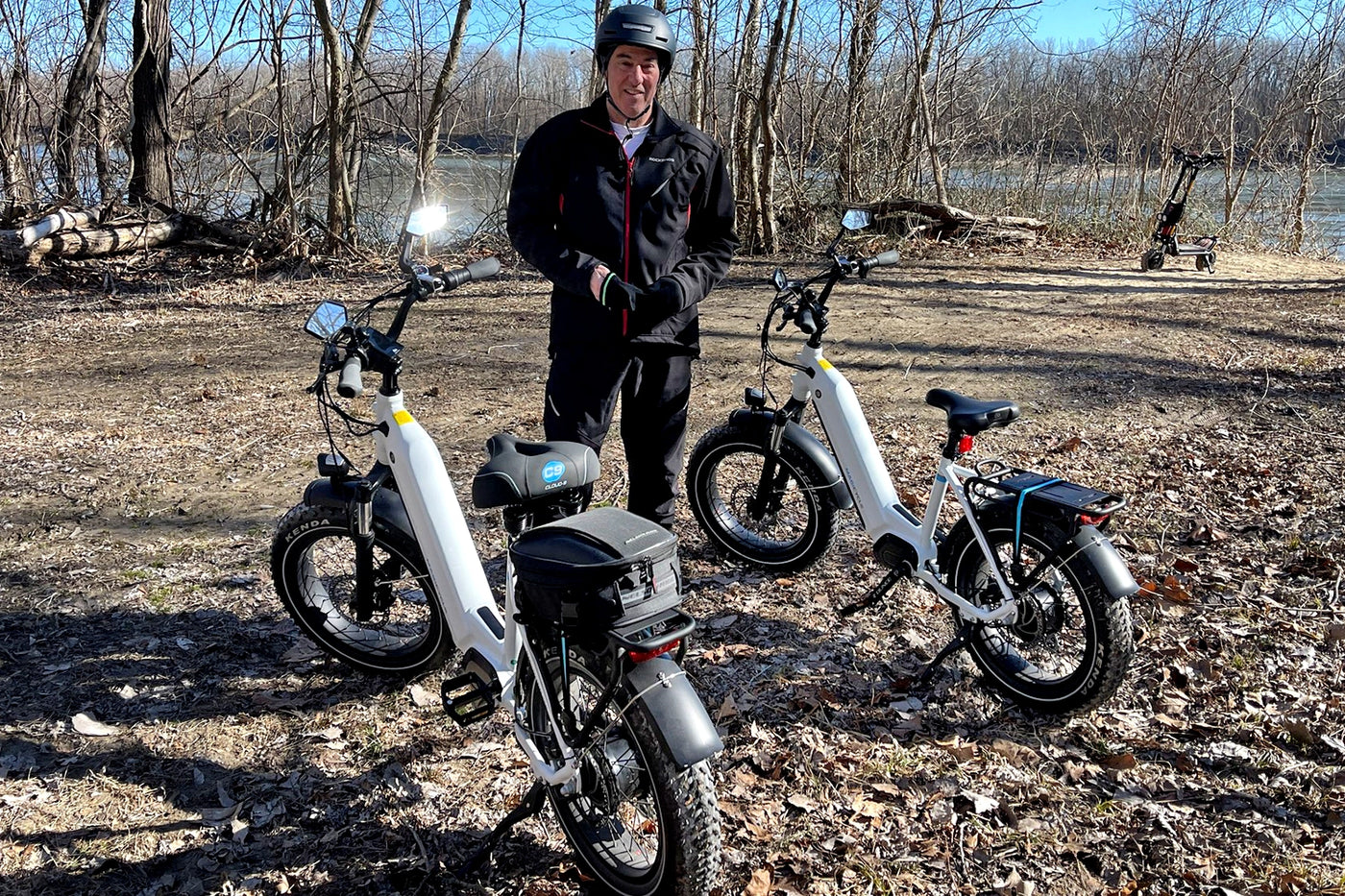 Person standing in a forest with two Magicycle electric bikes, highlighting their features.