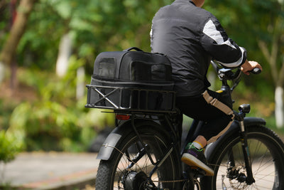 Man riding bike with black Magicycle pet carrier on rear rack, ideal for small pets